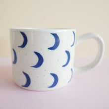 Load image into Gallery viewer, Speckled white ceramic mug with  hand painted blue crescent moons 
